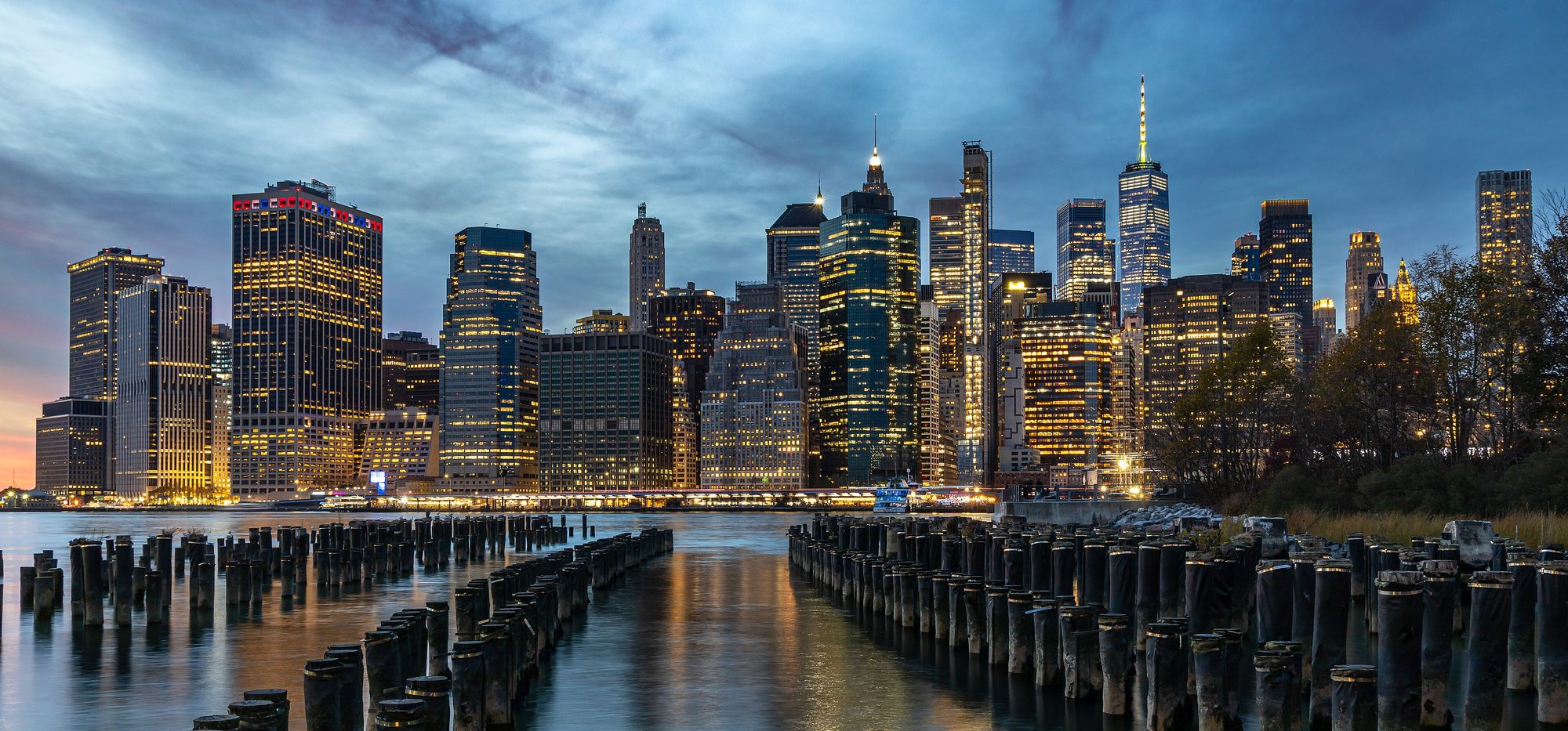 Lower Manhattan at blue hour, seen across the East River from the old pier pilings at Brooklyn Bridge Park.